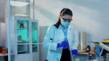Büyük biyoteknoloji laboratuvarında bilim kadını deney için kimyasal bir madde hazırlıyor. Çözümü karıştırıyor.