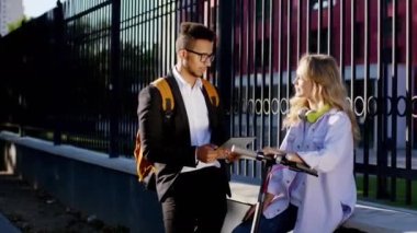 Üniversite kursundan sonra karizmatik genç öğrenciler caddenin ortasında durdular Afro-Amerikan adam elektronik tableti aldı ve iş arkadaşı bayan için bir şey göstermek için tartıştılar.