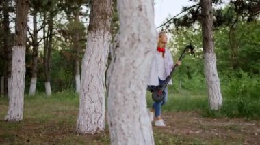 Vahşi parktaki sarışın kız çocuğu elektrikli scooterını eline aldı ve parkta mutlu mesut yürüyüp eğlenmeye başladı.