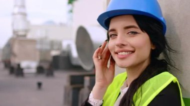Kadın mimar inşaat sahasının çatısında mola veriyor. Kocaman gülümsüyor ve kendini çok güzel hissediyor.