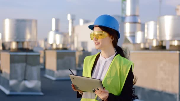 Ingegnere donna carismatico di fronte alla fotocamera sulla parte superiore del cantiere scattare alcune foto dal tablet digitale e utilizzando la razione per avere qualche conversazione con altri specialisti — Video Stock