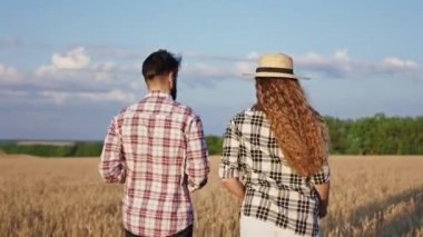 Güneşli bir günde kocasıyla birlikte yürüyen ve dijital tablet kullanarak tarım işleriyle ilgili bilgi edinen güzel bir kadın.