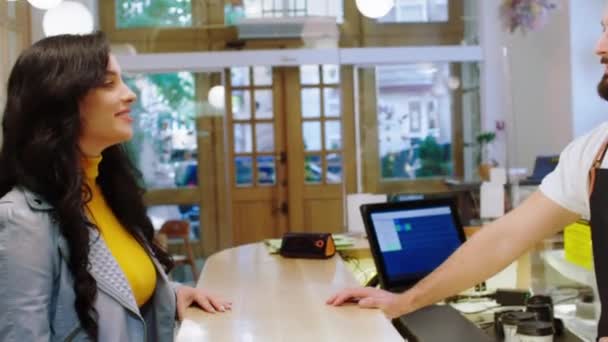 Vrouwelijke klant spreekt met de verkoper in de coffeeshop terwijl ze bereid is om te betalen — Stockvideo