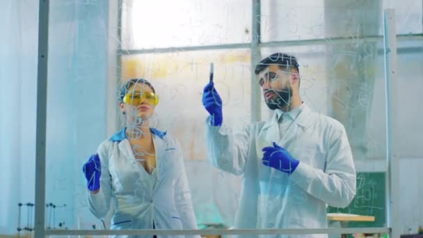 Mooie vrouw wetenschapper en man samen eindigen om het antivirusvaccin te onderzoeken ze schrijven de chemische formule op het transparante bord — Stockvideo