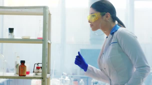 穿着防护服的女药剂师拿着一个装有生物技术和制药行业化学物质概念的玻璃瓶 — 图库视频影像