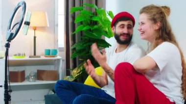 Karizmatik çiftler birlikte vakit geçirirken, kanepede otururken hafif bir yüzük kullanarak sosyal medya hesabı için canlı yayın yapıyorlar. 4k