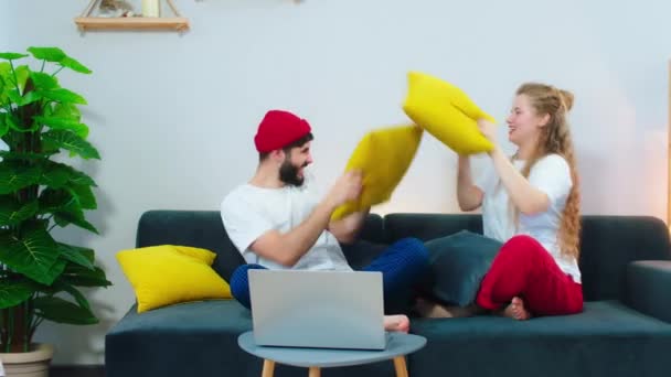 Tempo de diversão para um belo casal em casa na sala de estar aproveitando o tempo juntos eles têm uma batalha com travesseiros e sorrindo grande — Vídeo de Stock