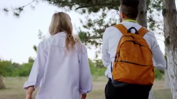 Twee studenten multiraciale na de college cursus lopen naar het park hebben een promenade het nemen van video van de achterste man met een elektrische scooter — Stockvideo