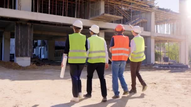Videót készítettek különböző szakemberek csoportjának hátuljáról az építkezés közepén, együtt elemezték az építkezés tervét. — Stock videók