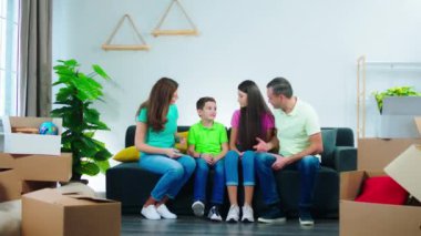 Yakışıklı, olgun ebeveynler ve çocukları yeni bir eve taşındılar oturma odasındaki kanepede tartıştılar.