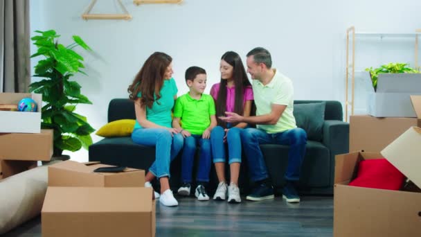 Krásná velká rodina se přestěhovala do nového domova sedí na pohovce v obývacím pokoji malý chlapec drží klíč od nového domu a šťastný úsměv všichni dohromady — Stock video