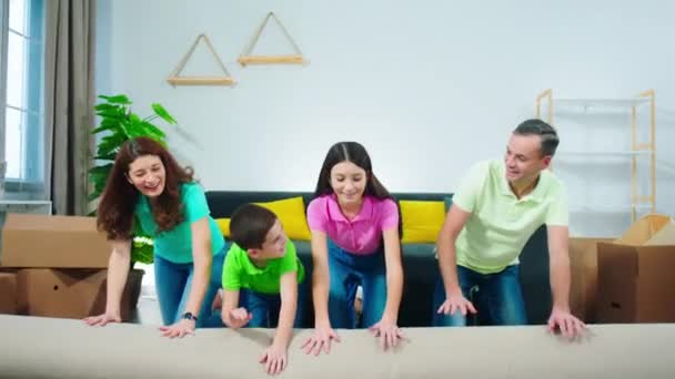 Gran familia carismática se mudó a un nuevo hogar toman la alfombra y se desenrollan en el suelo felices y emocionados delante de la cámara — Vídeos de Stock