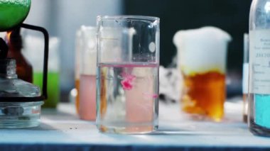 Laboratuvardaki bilim adamı deney tüpün içine pembe bir madde attı. Detayları kameraya yakın tutuyor.