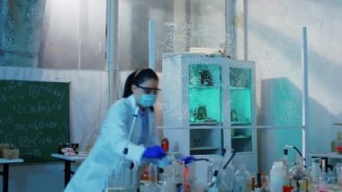 Karizmatik genç kadın eczacı eczacılık laboratuarında çok çalışıyor ve cam tüpe bazı kimyasal maddeler ekliyor.