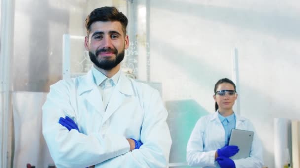 Carismático dos farmacéuticos hombre y mujer en el laboratorio de química posando delante de la cámara mirando recto y sonriente emocionado — Vídeos de Stock