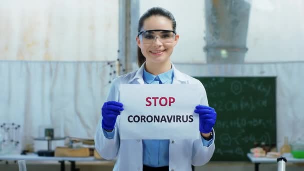 Looking straight to the camera smiling large woman scientist in the biochemical laboratory holding poster of Stop Coronavirus. Shot on ARRI Alexa Mini. — Stock Video
