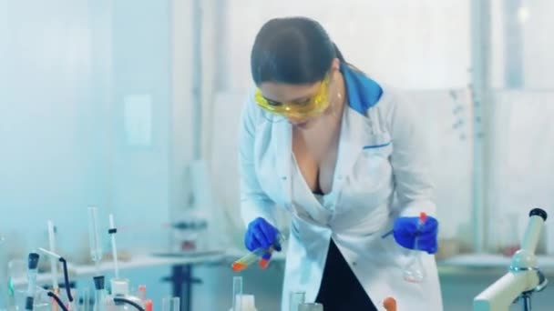 Niesamowicie wyglądająca naukowiec pani w laboratorium chemicznym pracuje nad budową eksperymentu przy użyciu proszku do produkcji reakcji chemicznych — Wideo stockowe