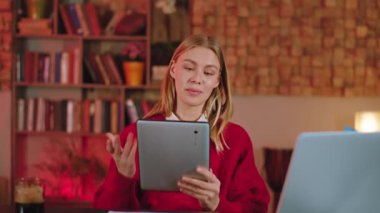 Kameranın önünde genç bir kadın iş görüşmesi yapıyor. Elektronik tabletle sohbet ediyor. El hareketleriyle bir şeyler anlatıyor.