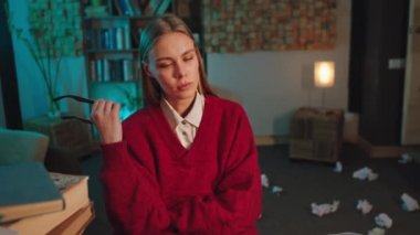 Karanlık ofisteki kadın çalışanın düşünen bir yüzü var. Gözlüğünü al ve daktiloyla yazmaya devam et.