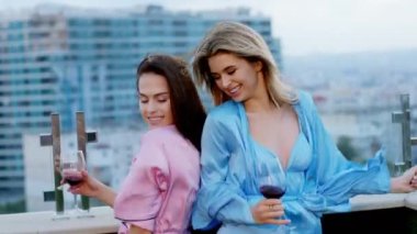 Akşam vakti çatı katının çatısında dans eden, şarap içen ve heyecanlanan iki harika kadın. ARRI Alexa 'da çekim