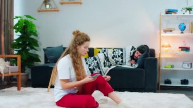 Elinde telefonla konuşan bir kadın, arkasında bir adam var. Battaniyeye sarılmış bir şekilde kanepeye uzanmış, içine hapşırıyor. Çok solgun ve hasta görünüyor.