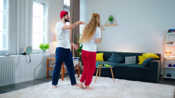 現代のリビングルームでは、幸せと良いカップルは、自宅のダンスで瞬間を楽しんで見て、パジャマで恋に感じています。ARRI Alexaで撮影 — ストック動画