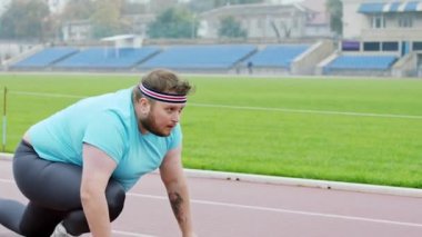Stadyumdaki başlangıç çizgisinde iyi görünümlü obez adam sıkı bir maratona hazır ol.