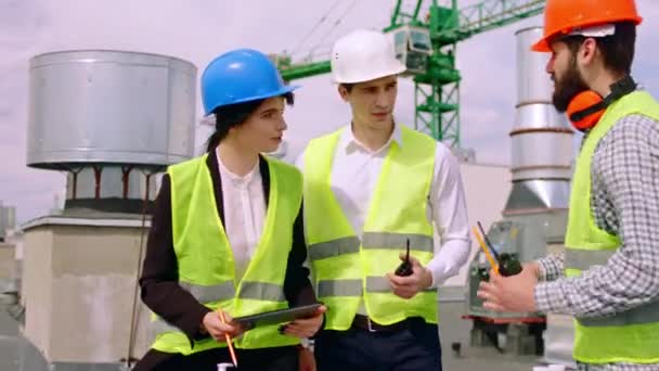 Charyzmatyczny biznesmen i jego inżynier zespołu budowlanego i architekt w kaskach bezpieczeństwa na szczycie budynku spotykają się, aby omówić plan budowy. 4k — Wideo stockowe
