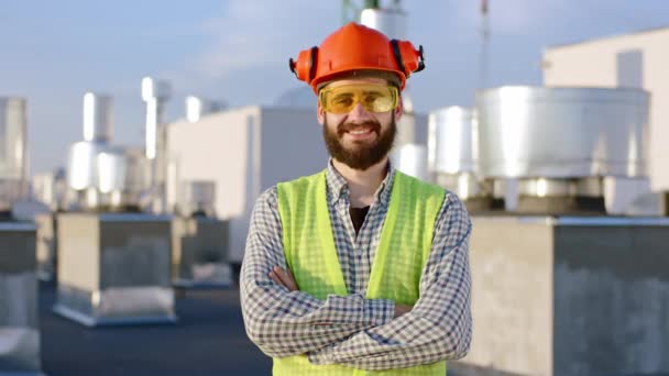 Porträtt av en leende stor byggare man med en säkerhetsutrustning han poserar framför kameran ler stora och glada — Stockvideo