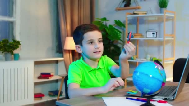 Atraente bonito menino pequeno ao fazer sua escola lição de casa on-line jogando com um avião na frente da câmera — Vídeo de Stock