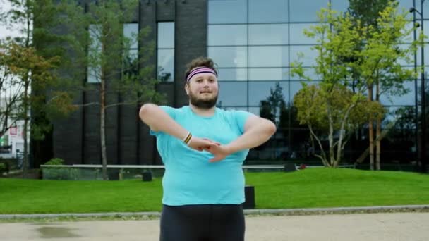 Obese guy get ready to start a aerobic workout he stretching hands and body before to start he wearing yoga outfit — Stock Video