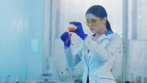 Laboratorio di biochimica bella signora scienziata utilizzando tubo di vetro per fare un esperimento ha aggiunto un po 'di liquido giallo analizzando la reazione. 4k — Video Stock