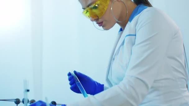 Atraktivní žena vědec velmi koncentrované pomocí některých zkumavek z testovacího skla, aby experiment v chemické laboratoři — Stock video