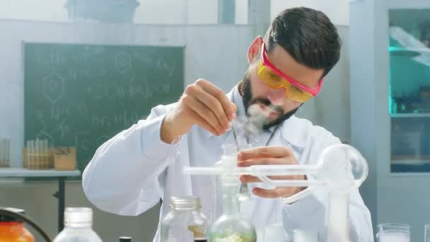 Koncentrerad forskare man i hans kemiska laboratorium ta några kemiska vätskor för att göra en reaktion för hans testkoncept för biokemi och läkemedelsindustrin — Stockvideo
