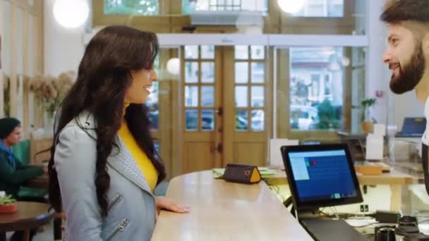 Charismatische verkoper man geeft twee kopjes afhaalkoffie aan de verbazingwekkende uitziende klant ze hebben een vriendelijk gesprek — Stockvideo