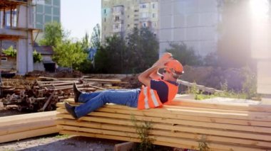 Foreman öğle yemeği saatinde şantiyede uyukluyor. Gözlük ve kaskla işe gidiyor.