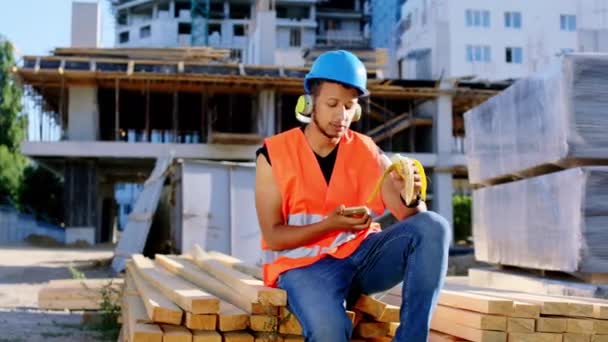 Al cantiere afro americano molto carismatico ascoltare musica alla pausa e mangiare una banana indossa attrezzature di sicurezza — Video Stock