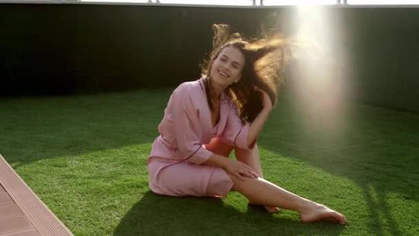 Güneşli bir sabah, pijamalı güzel bir kadın kameranın önünde poz veriyor. — Stok video