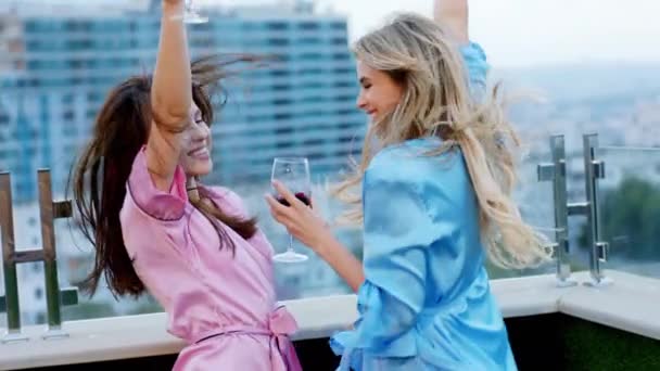 Sonriendo hermosas mujeres en la parte superior de la terraza loft que beber un poco de vino y sentirse emocionado en pijama — Vídeo de stock