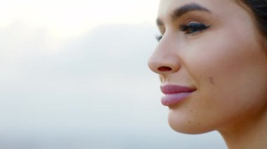 Fotoğraf makinesinin yakınındaki inanılmaz görünüşlü kadın, uzaklardaki bir apartmanın çatısına bakıyor.