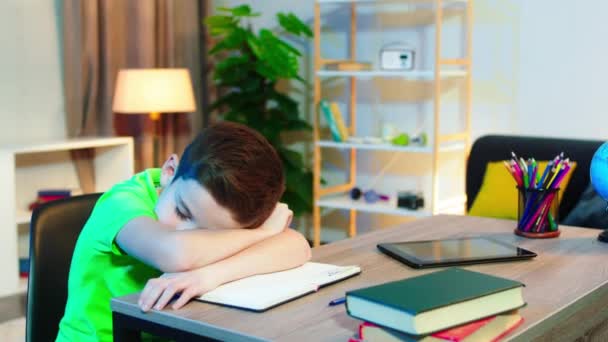 Śpiący i zmęczony chłopiec leżący na stole w pokoju, a następnie wstań i przygotuj się do rozpoczęcia prac domowych w szkole. 4k — Wideo stockowe