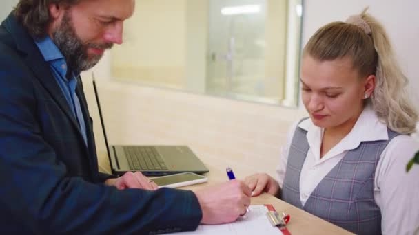 Recepção clínica assistente muito feminino e homem paciente analisando a história da consulta e fazer algumas mudanças. Tiro em arri alexa mini — Vídeo de Stock