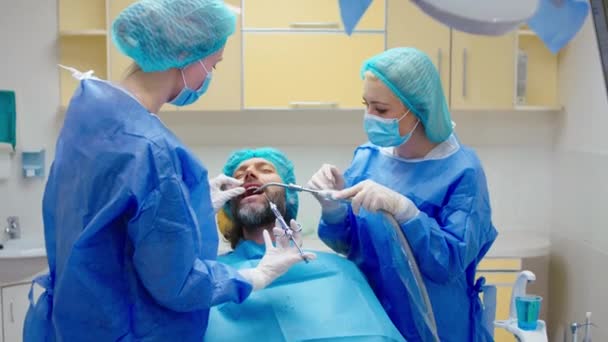 Clinica dentale dentista femminile e la sua assistente fanno un trattamento di cura orale per un paziente maturo uomo carismatico che lavorano concentrato — Video Stock