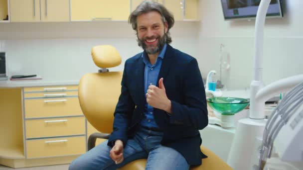 Šťastný a usměvavý velký trpělivý muž po návštěvě zubaře ukazuje velké jako na kameru — Stock video
