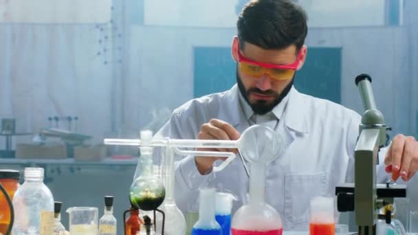 Vor der Kamera konzentriert Wissenschaftler Mann in seinem Chemielabor arbeitet er mit Glaswannen und etwas chemischer Flüssigkeit, um ein Experiment zu machen. 4k — Stockvideo