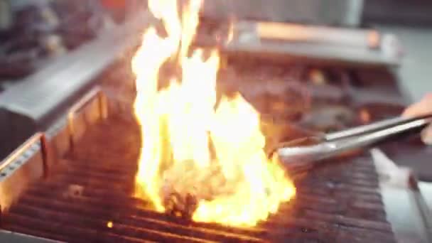 厨师在摄像机前的专业烤架上准备牛肉牛排，他在烤肉上加了些火来把牛排煮熟 — 图库视频影像