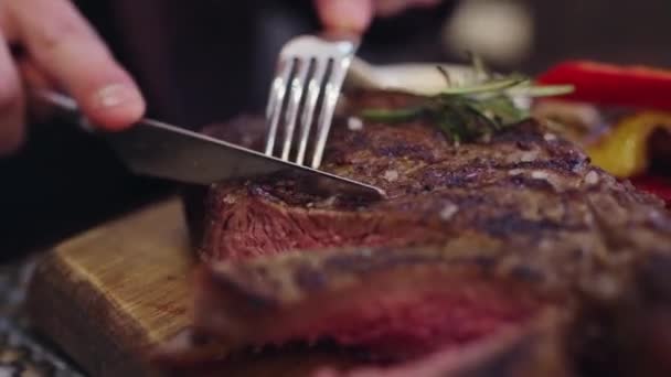 Primer plano del camarógrafo tomar un cuchillo y cortar el filete de carne jugosa en el restaurante que disfrutó de la cena — Vídeos de Stock