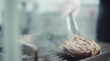 Delicious beef steak cooking in front of the camera on professional grill by the main chef of restaurant