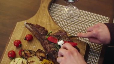 A man take his dinner in the restaurant he order a plate of vegetables with beef steak he take a knife and start cut off