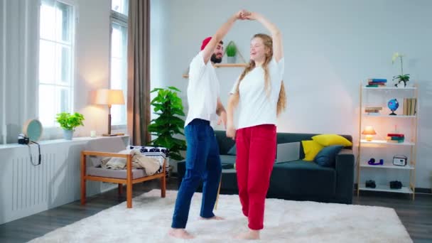 Smiling large charismatic couple feeling happy and relaxed at home dancing romantic together in a modern large living room they hugging each other at the end — Stockvideo